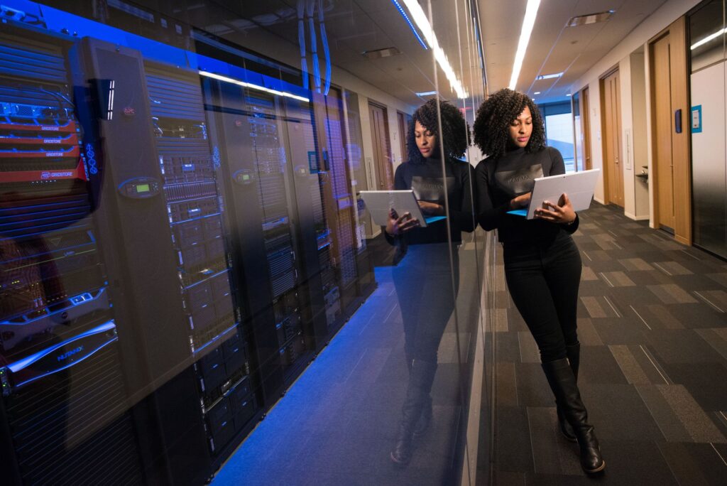 System administrator working on Linux terminal in front of rows of servers in a futuristic data center